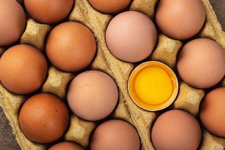  Broken egg with whole eggs in box. Top view.の写真素材