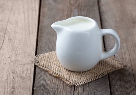 White jug with milk on a wooden rustic backgroundの写真素材