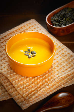 Bowl of tasty pumpkin soup and space for text on brown table, top viewの写真素材