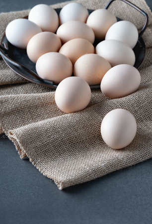 Chicken eggs in metal tray on burlap background.