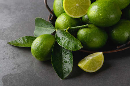 Fresh green limes with leaves on a trayの写真素材