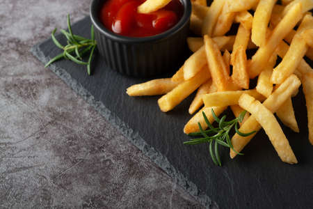 Homemade baked french fries on a black slate board.の写真素材