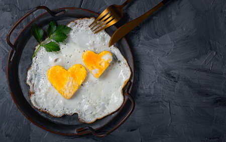 Homemade fried egg in a vintage pan a gray background. Heart-shaped yolk.View from above. Copy space for text.の写真素材