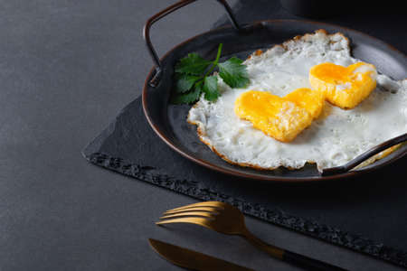 Homemade fried egg in a vintage pan a gray background. Heart-shaped yolk. Copy space for text.の写真素材