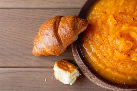 Pumpkin puree and croissant on a wooden table. Copy spaceの写真素材