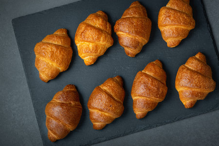 Group of croissant arranged in two rows and ready at the table for breakfast