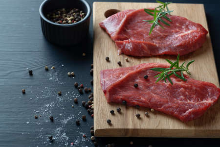 Fresh meat with ingredients for cooking on dark tableの写真素材