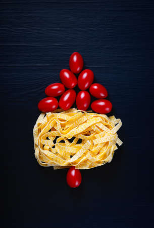 Pasta nest with tomatoes on a dark backgroundの写真素材