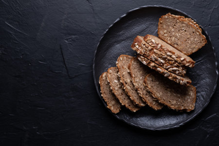 Sliced rye bread on a black table. Whole grain rye bread with seeds
