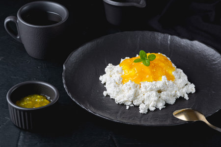 Lemon jam with cottage cheese in black bowl closeup