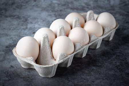Carton box with eggs on grey table