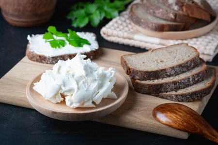 Home made bread on a wooden cutting board with curd cheese and ricottaの写真素材