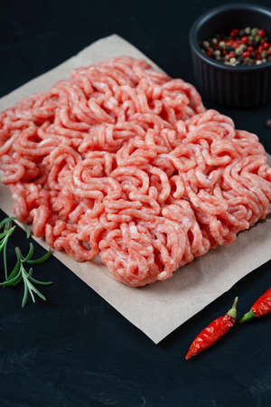 Fresh raw minced beef on backing paper and cutting board and ingredientsの写真素材