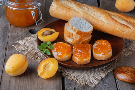 Toasts of bread with apricot jam and fresh fruits with mint on an wooden table.