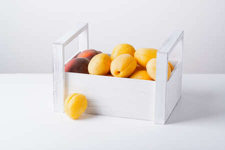 Wooden box with apricots and peaches isolated on white backgroundの写真素材