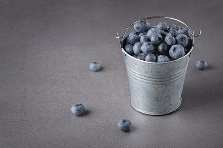 Fresh blueberries in small bucket on the gray table. Copy spaceの写真素材