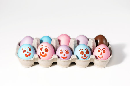 Colorful funny easter eggs with face in a egg box. Copy space