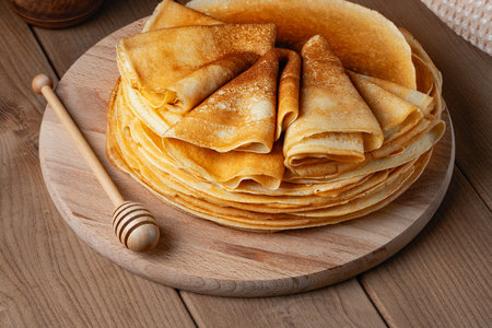 Thin pancakes on a wood plate. Homemade crepes, tasty food. Staple of yeast pancakes, traditional for Russian pancake week (Shrove tide). Thin pancake with crispy crustの写真素材