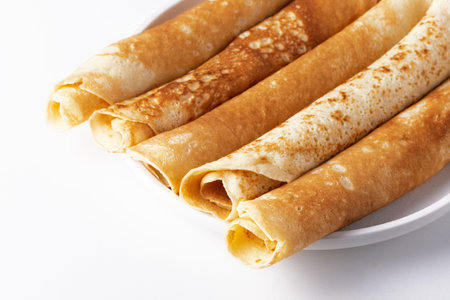 Thin pancakes rolled into a roll on a plate. The concept of a delicious breakfast or Maslenitsa.