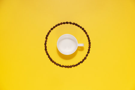 Empty coffee cup and coffee beans on yellow background.の写真素材