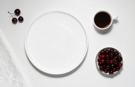 Empty white plate, coffee and cherry on white tableの写真素材