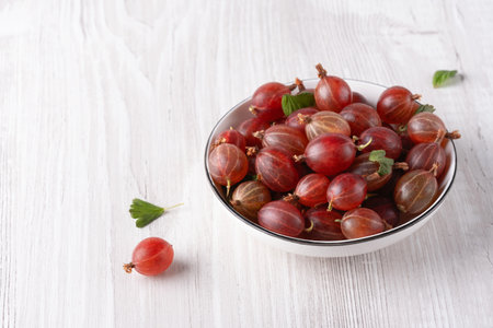 Fresh, sweet red gooseberries in a white cup on a white background, with copy space for text.の写真素材