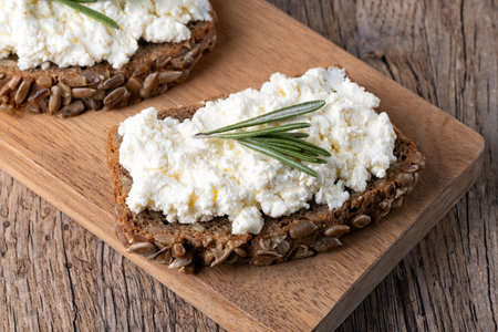 Home made rye bread on a wooden cutting board with curd cheeseの写真素材