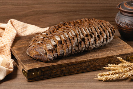 Sliced rye bread on a rustic cutting board and rye ears