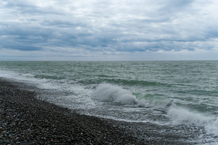 Peaceful ocean waves lapping at the rocky shoreline under a cloudy sky during early evening hours