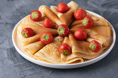 Pancakes with strawberries on a grey tableの写真素材