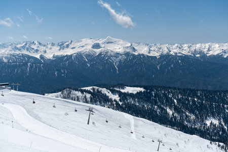 Snowy mountain landscape with ski lifts and clear blue sky in winter season