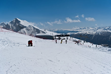 Snowy mountain landscape with skiers enjoying sunny day in mountains - Rosa Peak, Russia April 15,...