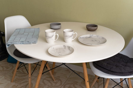 Modern dining table set for a casual meal with marble-patterned plates and cups in a cozy kitchen