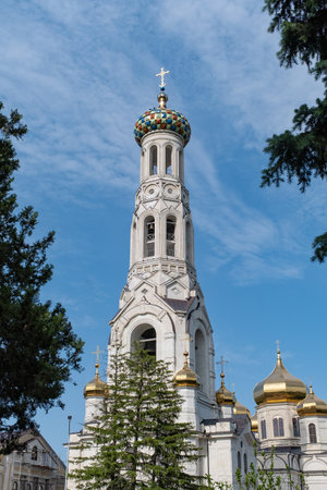 Beautiful bell tower with colorful dome rises above surrounding trees in a serene landscapeの写真素材