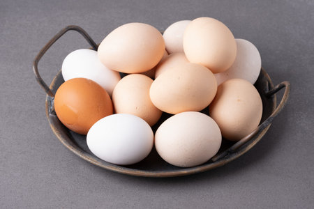 Collection of fresh eggs in a rustic bowl on a gray surface