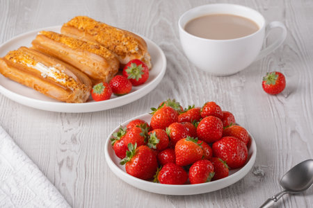 Fresh strawberries and pastries on a table with a cup of coffee in the morningの写真素材