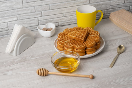 Waffles made in a heart shape served on a plate with honey and syrup nearbyの写真素材