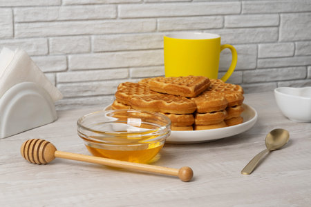 Waffles made in a heart shape served on a plate with honey and syrup nearbyの写真素材