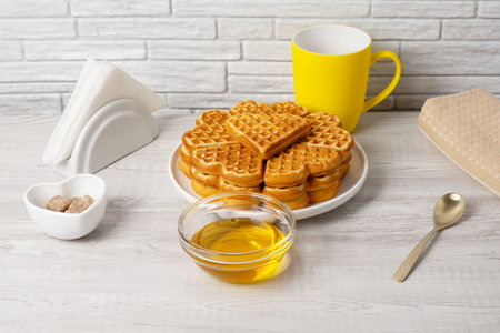 Waffles made in a heart shape served on a plate with honeyの写真素材
