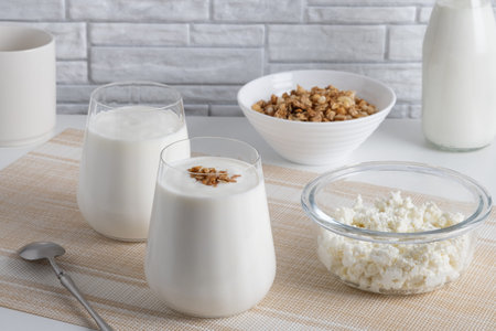 Kefir, buttermilk or yogurt, cottage cheese with granola. Yogurt in glass on white wooden background.の写真素材