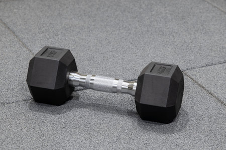 A dumbbell lies on the gray floor in the gymの写真素材