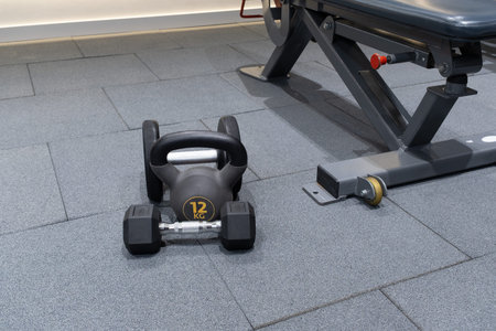 Dumbbells and kettlebell placed on the gym floor for exercise at a fitness center during daytimeの写真素材