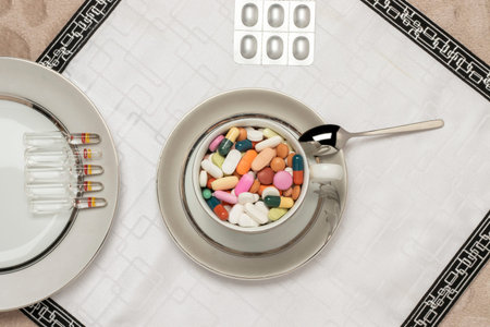 Colorful pills disease and treatment concept image in plate and glass on close-up dining tableの写真素材