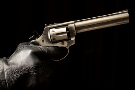 black background close-up black leather glove held dangerous knife and firearm consept visual designの写真素材