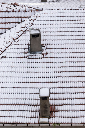 view of snow falling on the building roof in winterの写真素材