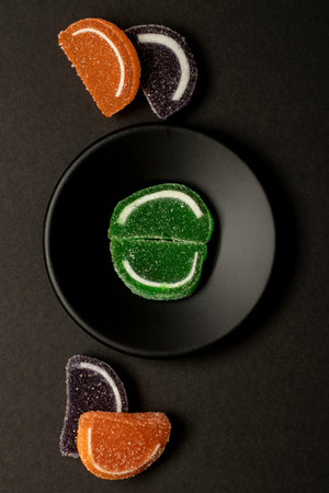 Delicious sweet soft candy concept with colorful fruits in black plate on a black background...