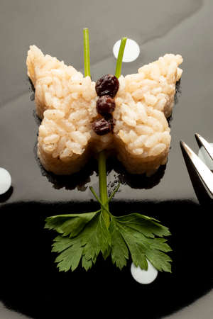 Close-up view of sushi with rice pilaf and parsley in the shape of a butterfly on a black backgroundの写真素材