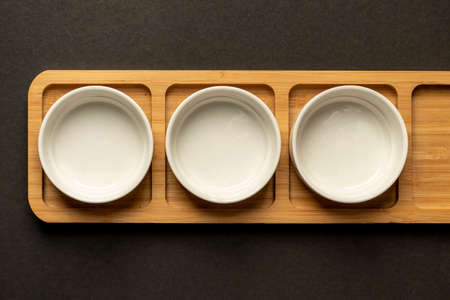 concept of colorful macaroons with fruit flavor on wooden plate against black backgroundの写真素材