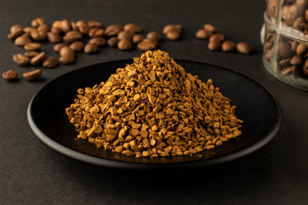 Grain coffee beans and Nescafe in dish on a black background close-up studio concept
