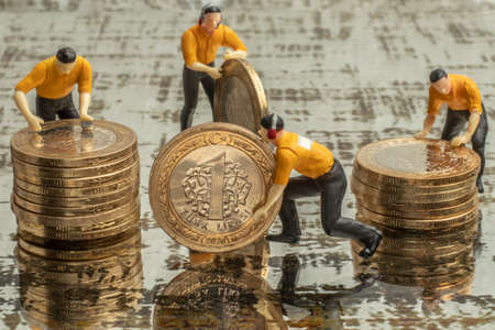 financial economy concept with miniature human figures and coinsの写真素材